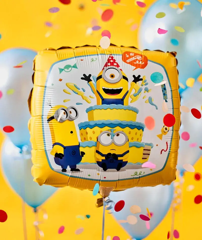 A bright yellow square balloon featuring cartoon minion characters around a birthday cake, surrounded by confetti and blue balloons on a sunny yellow background.